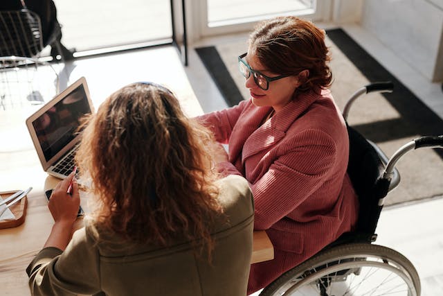 two-people-at-a-table-one-of-them-in-a-wheelchair